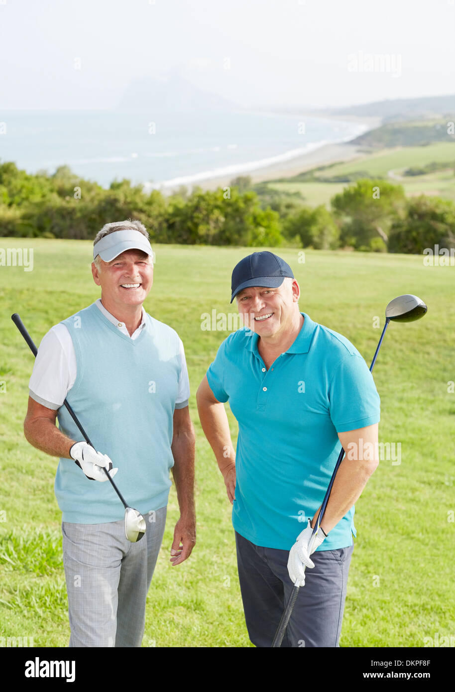 Senior uomini sorridenti sul campo da golf con vista sull'oceano Foto Stock