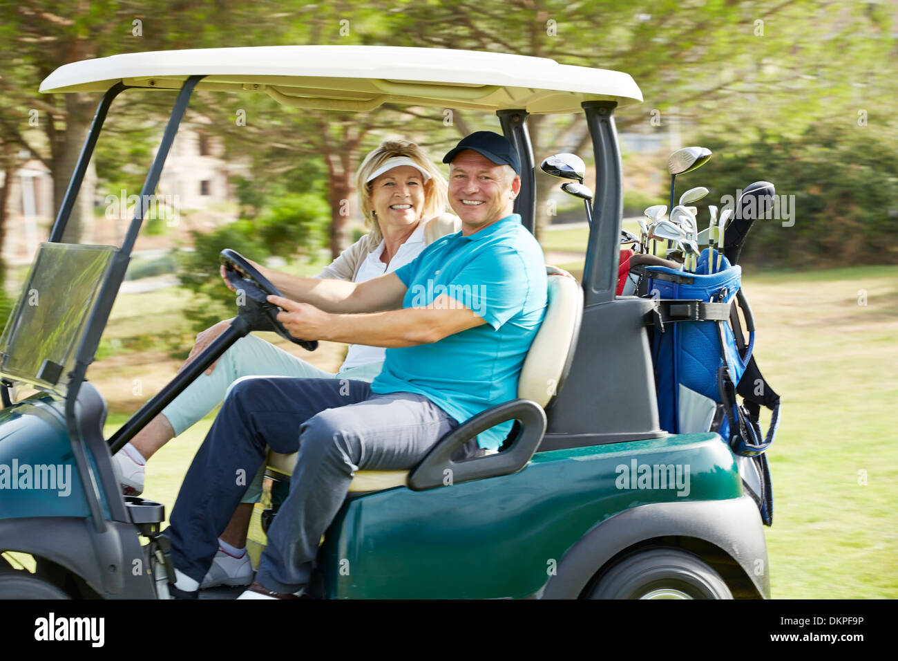 Coppia senior la guida carrello da golf sul corso Foto Stock