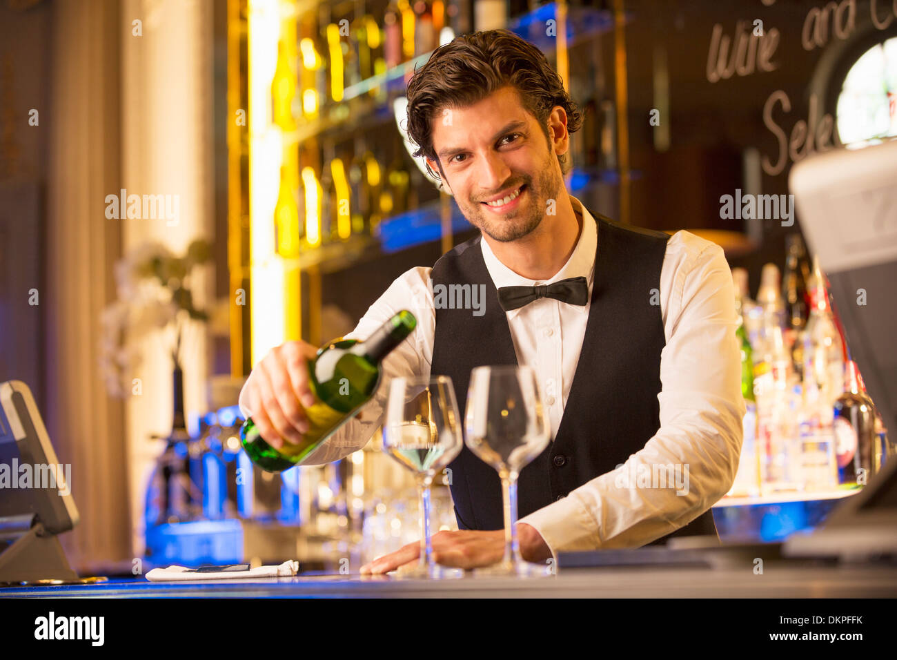 Ritratto di ben vestito barista versando il vino nel bar di lusso Foto Stock