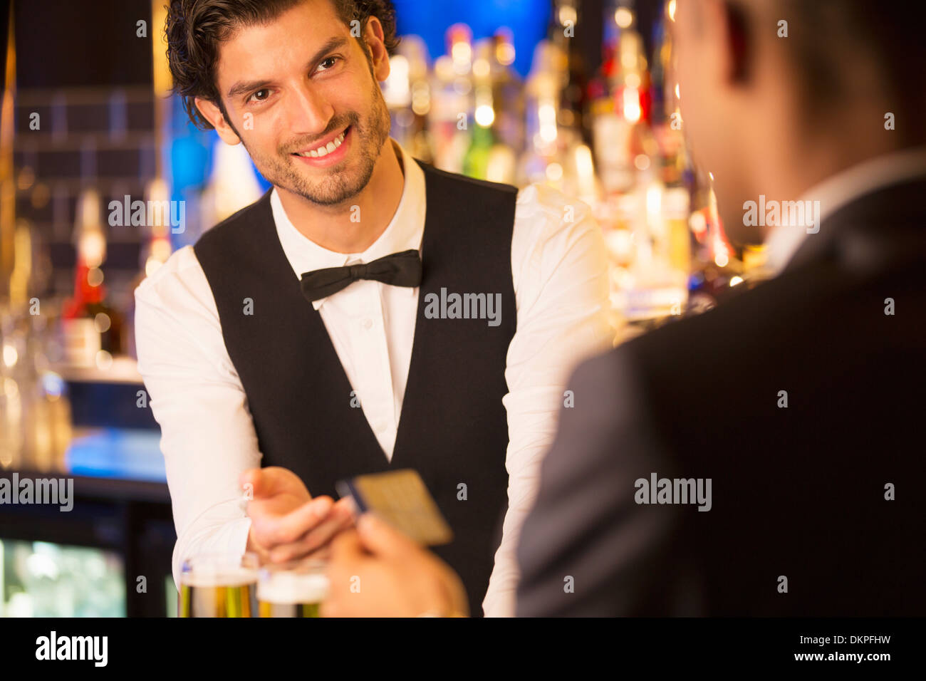 Ben vestito barista prendendo carta di credito dal cliente nel bar di lusso Foto Stock