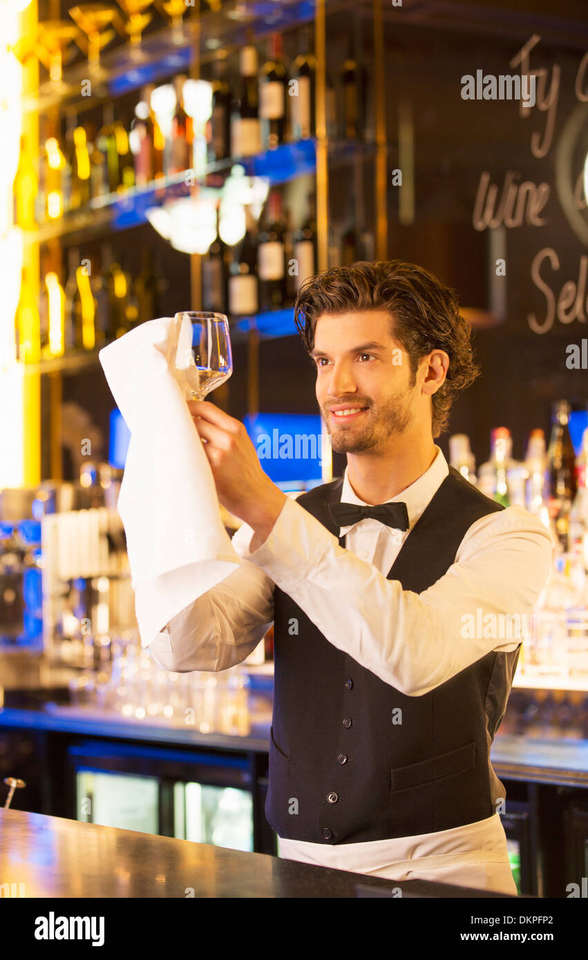 Ben vestito barista tergi vetro del vino nel bar di lusso Foto Stock