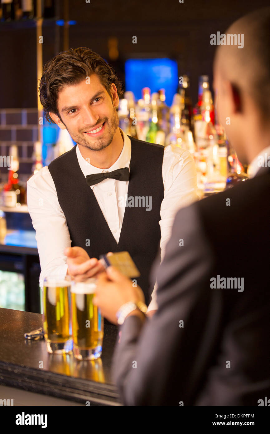 Ben vestito barista prendendo carta di credito dal cliente nel bar di lusso Foto Stock