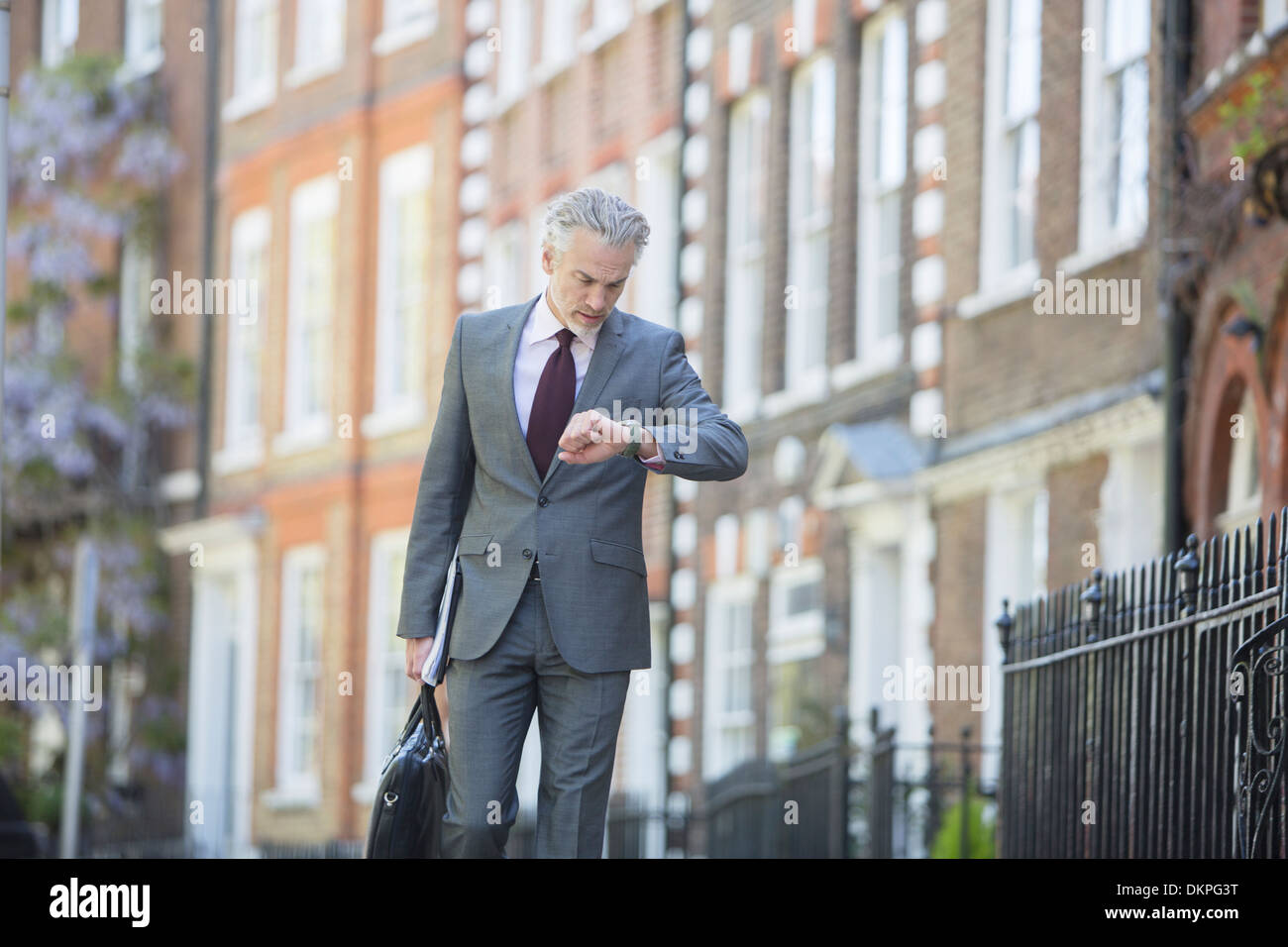 Imprenditore controllo orologio da polso sul marciapiede urbano Foto Stock