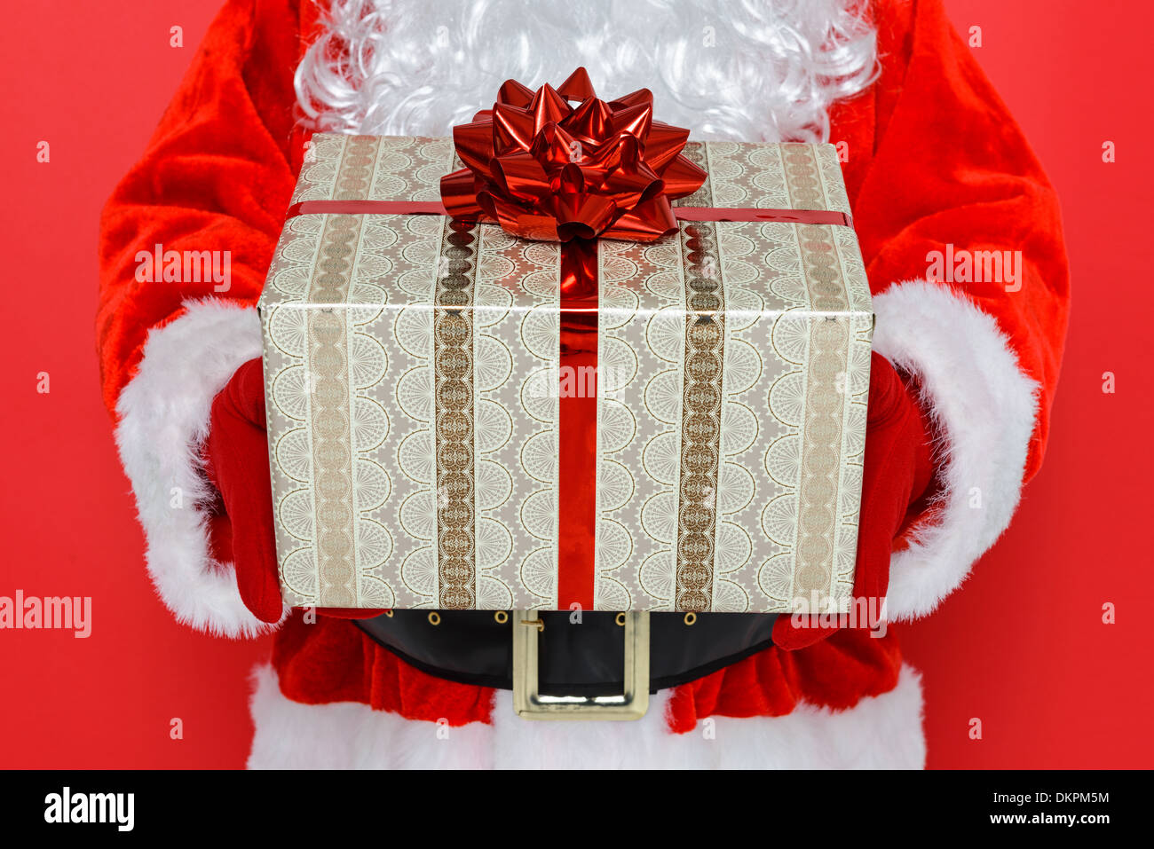 Santa Claus o Babbo Natale ti dà un regalo presente, sfondo rosso. Foto Stock