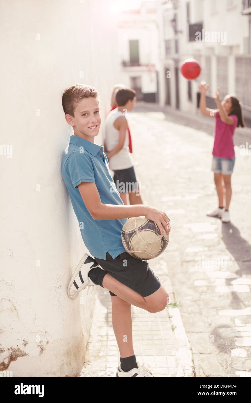 Ragazzo tenendo palla calcio in vicolo Foto Stock