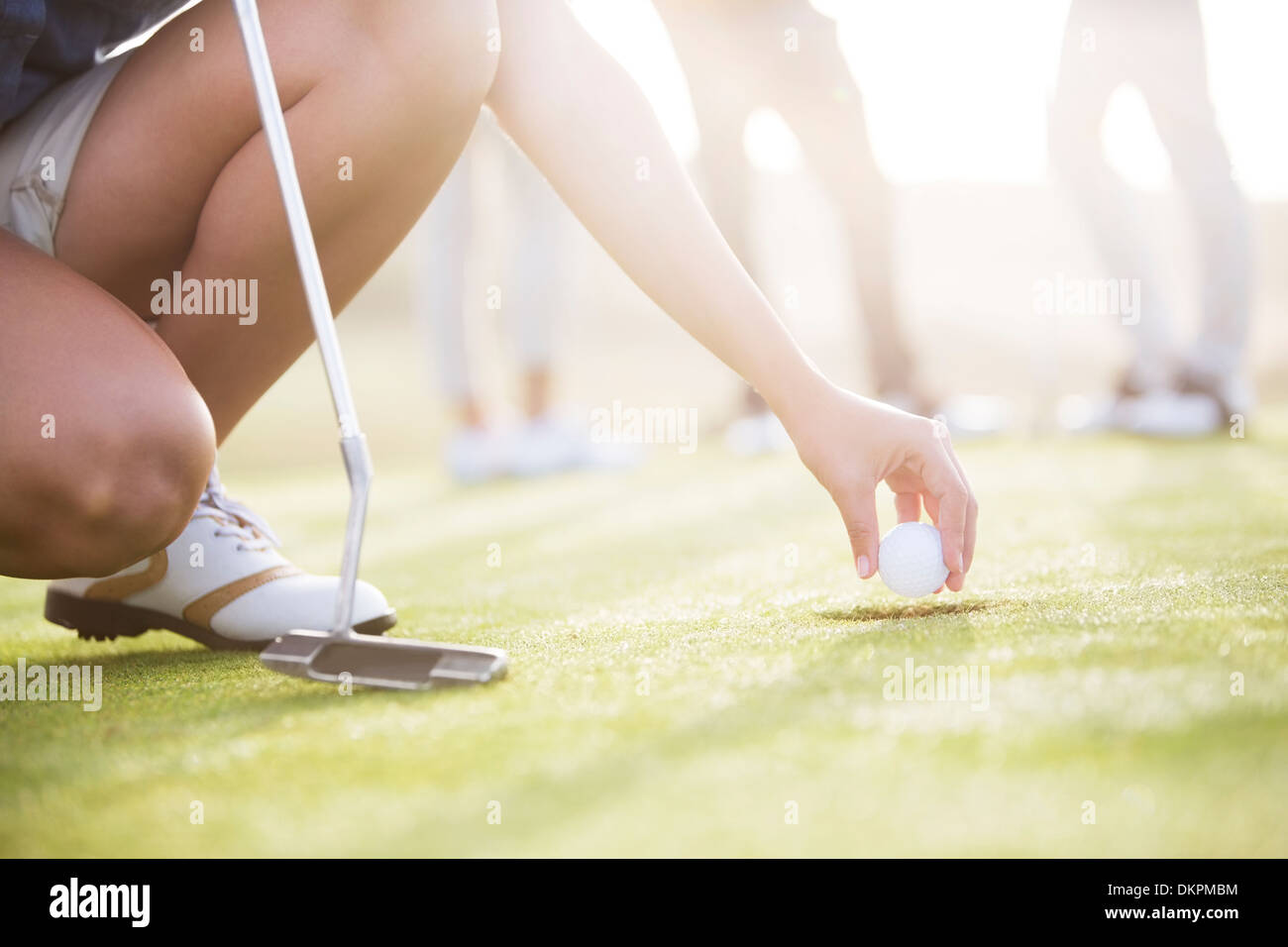 Donna rimozione pallina da golf dal foro Foto Stock