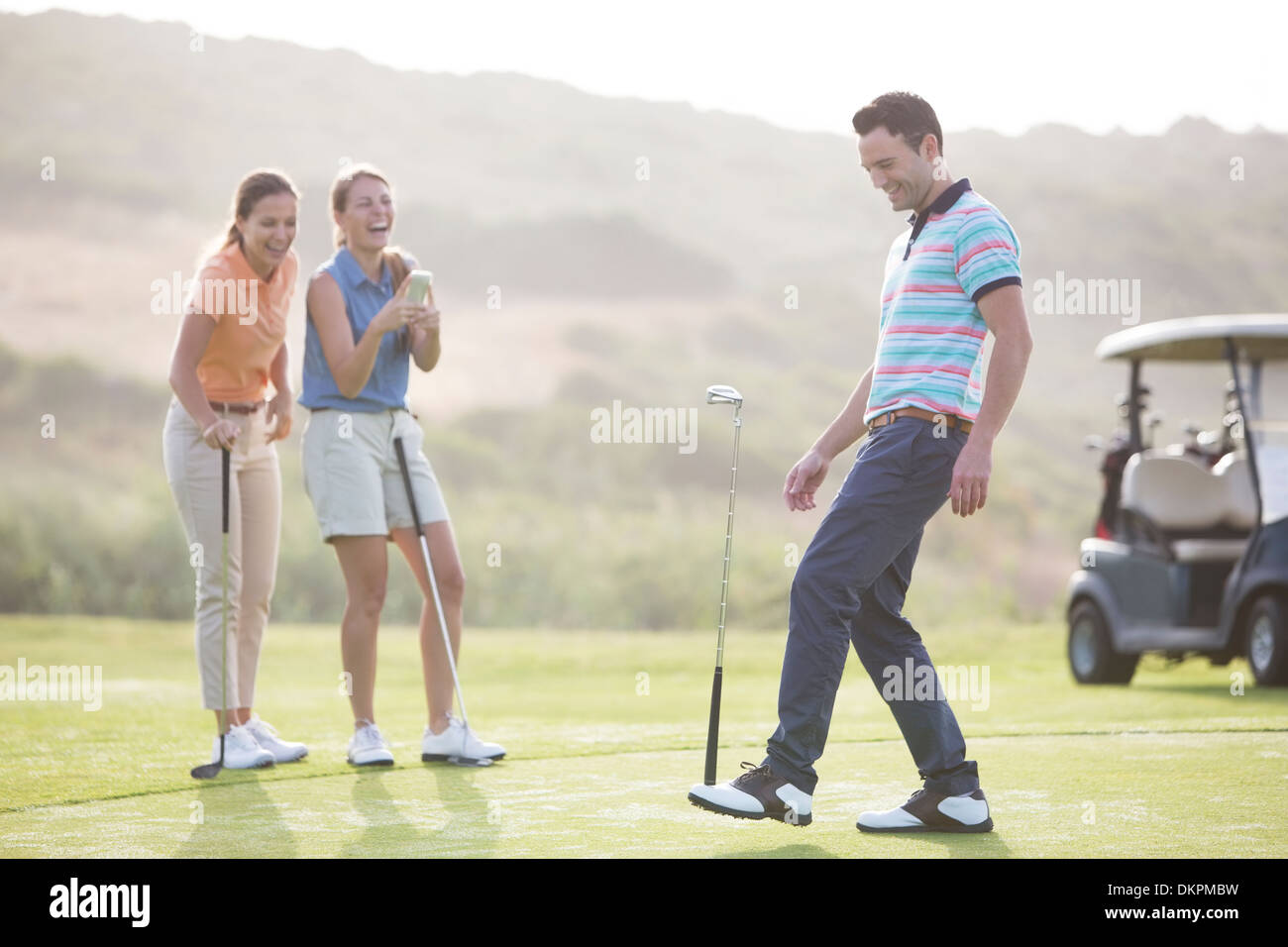 Le donne a guardare l uomo saldo golf club a piedi Foto Stock