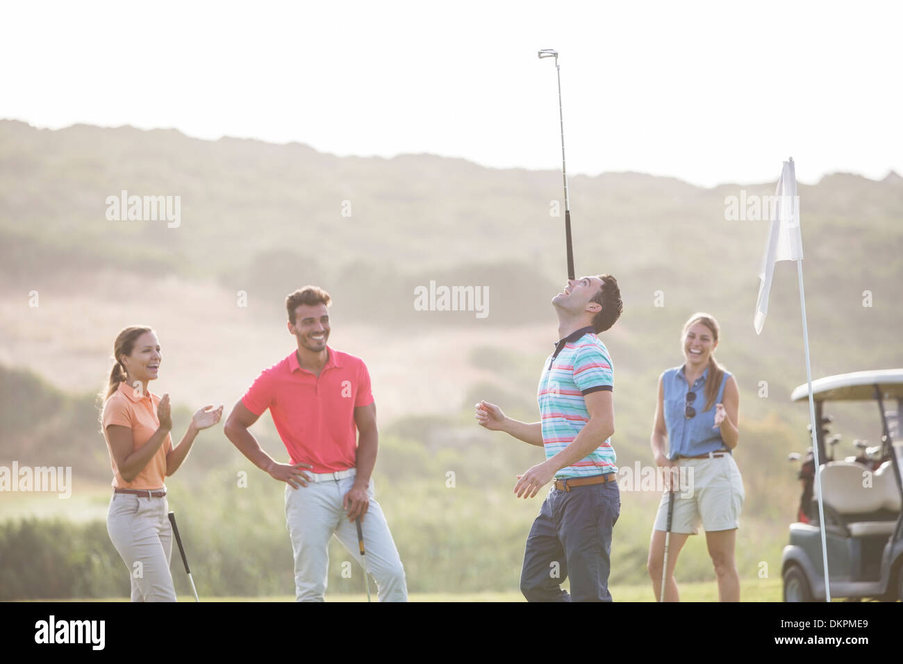 Gli amici a guardare l uomo saldo golf club a naso Foto Stock