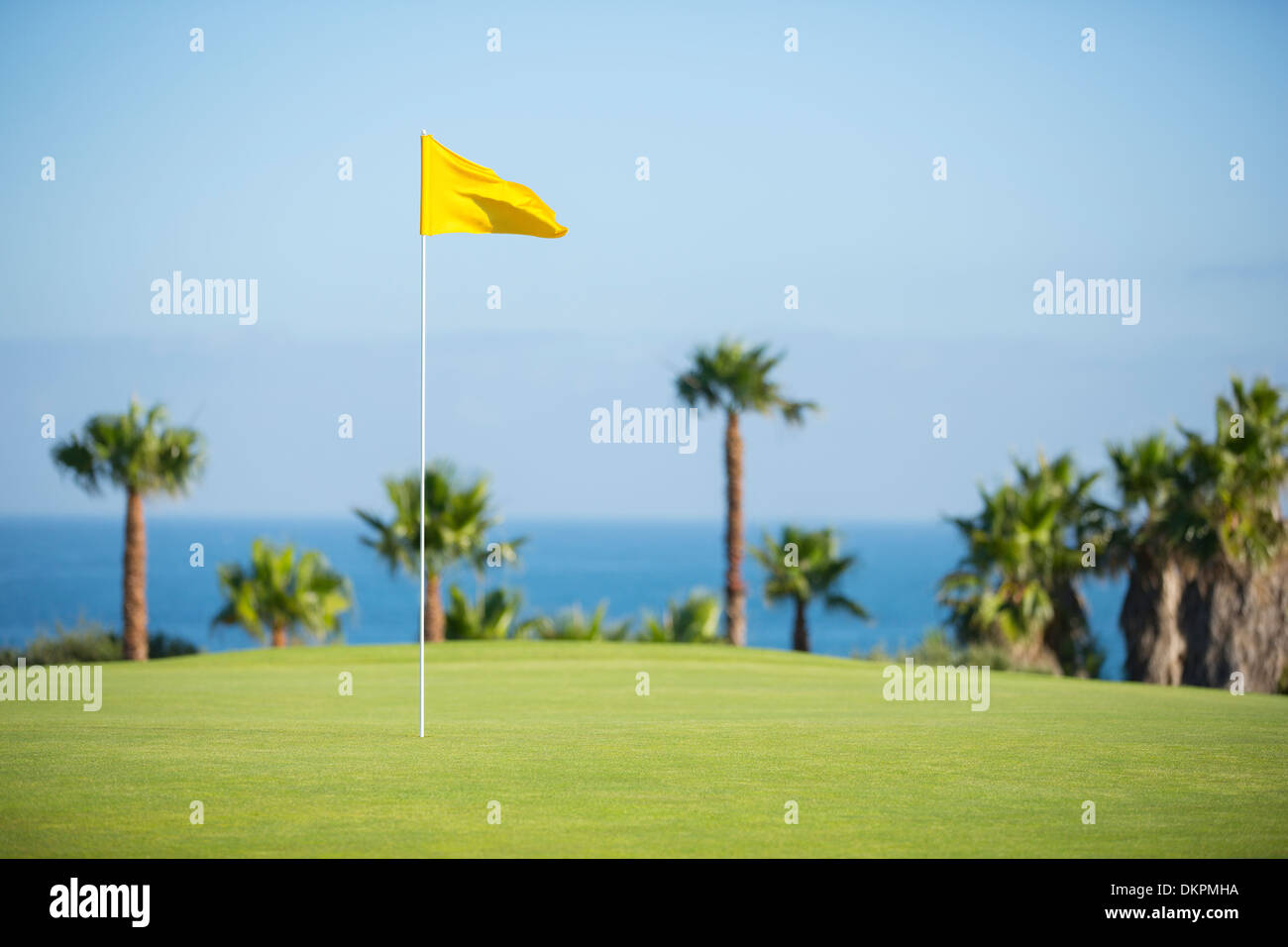 Il flag nel foro sul campo da golf con vista sull'oceano Foto Stock