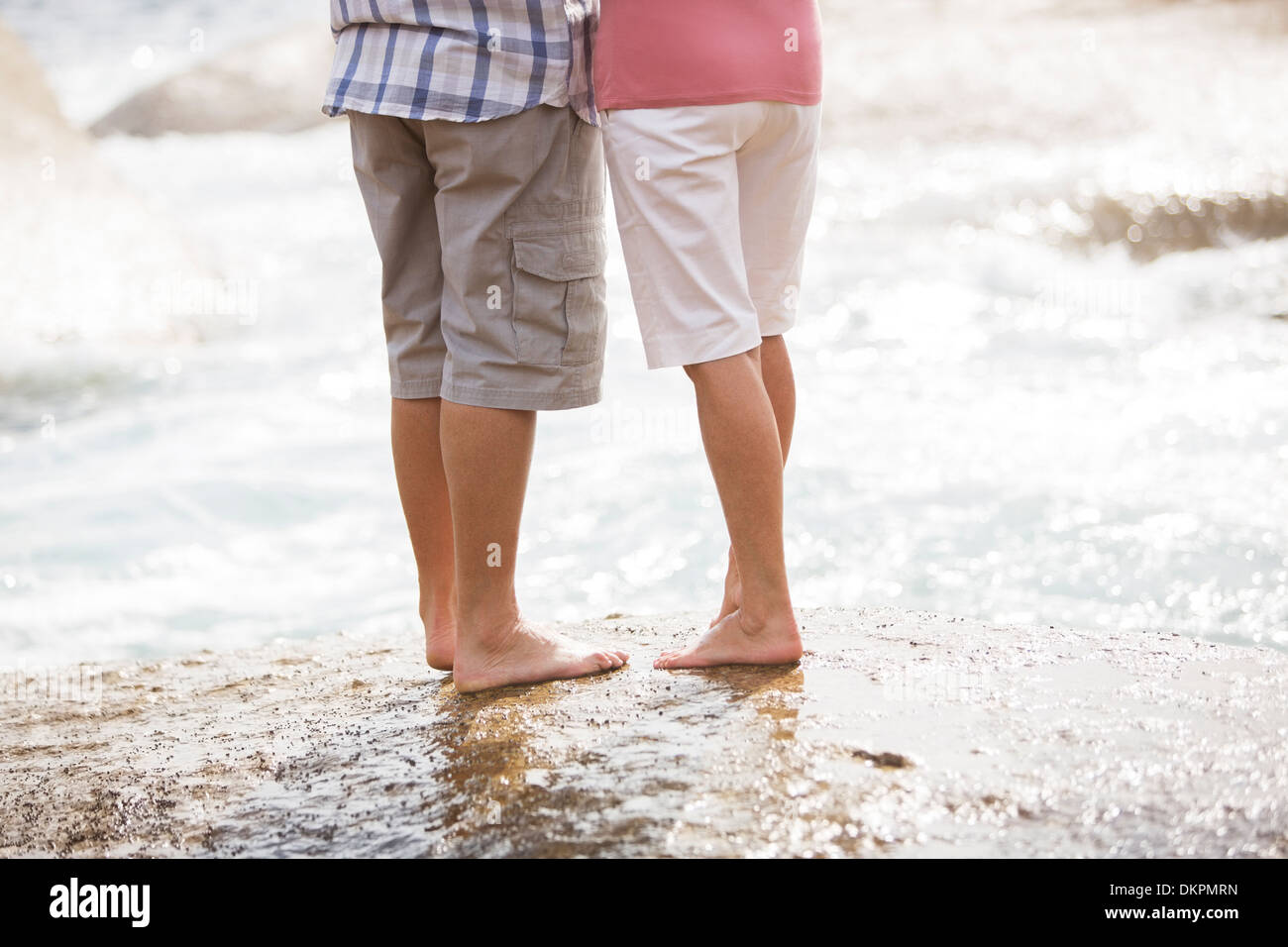 Coppia senior permanente sulla roccia alla spiaggia Foto Stock