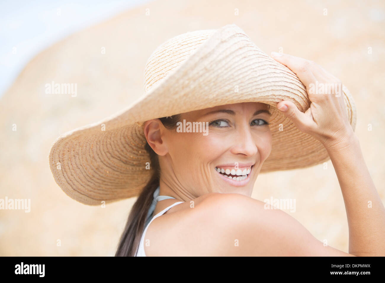 Donna che indossa cappello di paglia sulla spiaggia Foto Stock