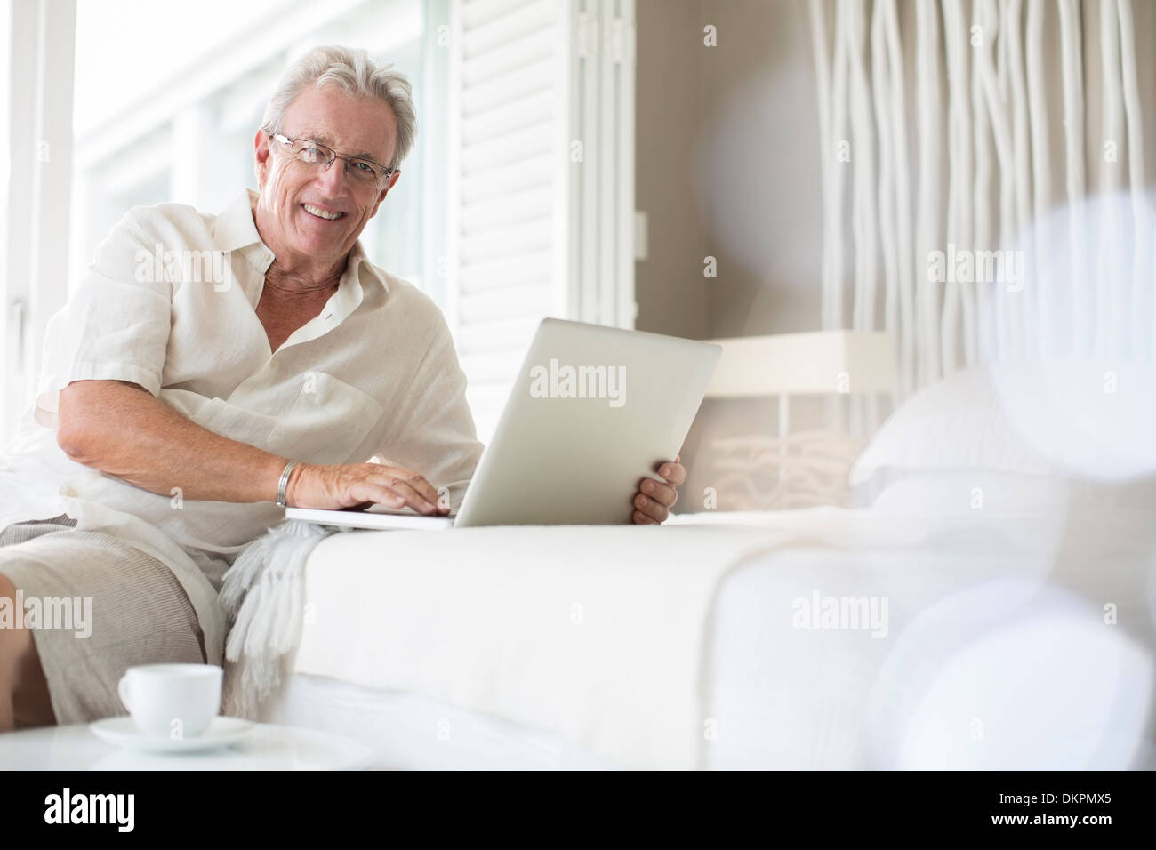 Uomo anziano utilizzando laptop sul letto Foto Stock