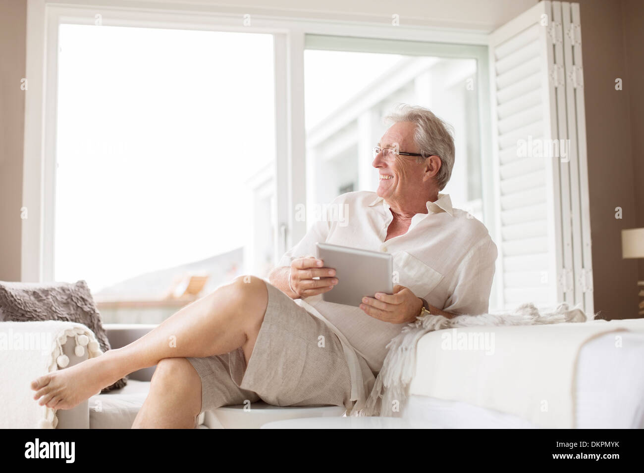 Uomo anziano con tavoletta digitale in camera da letto Foto Stock