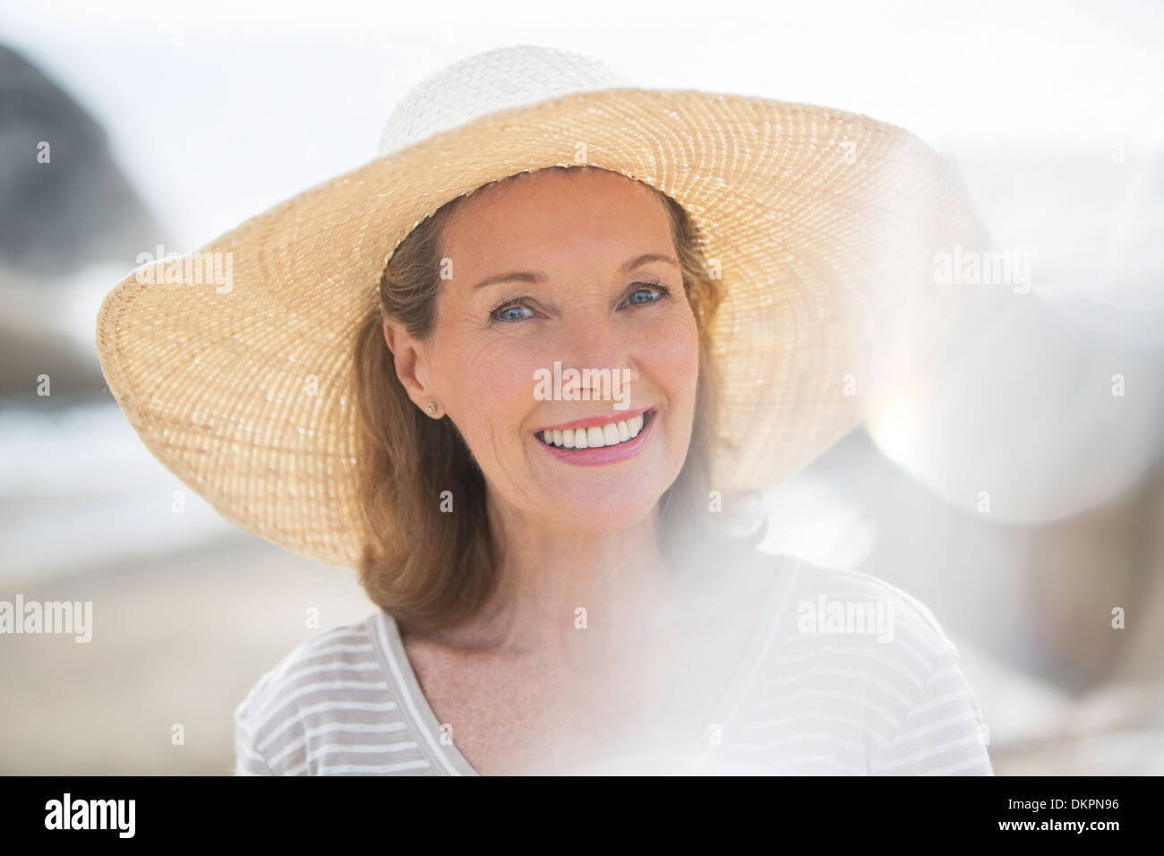 Donna anziana indossando cappello di paglia sulla spiaggia Foto Stock