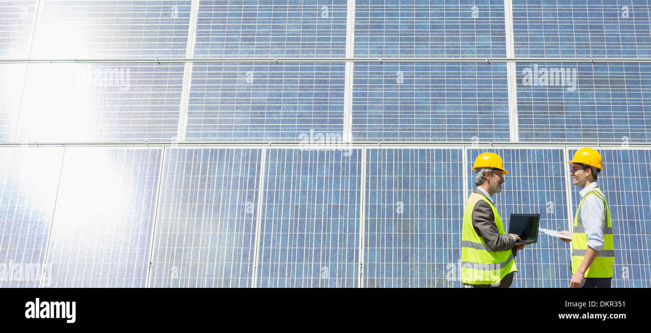 Lavoratori esaminando i pannelli solari nel paesaggio rurale Foto Stock
