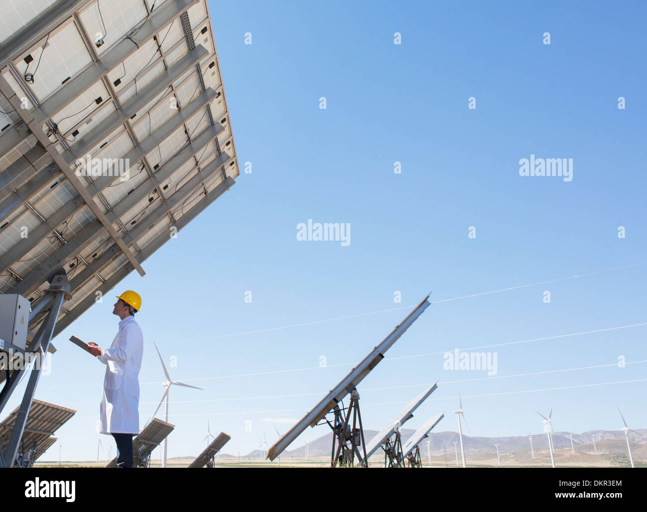 Scienziato esaminando pannello solare nel paesaggio rurale Foto Stock