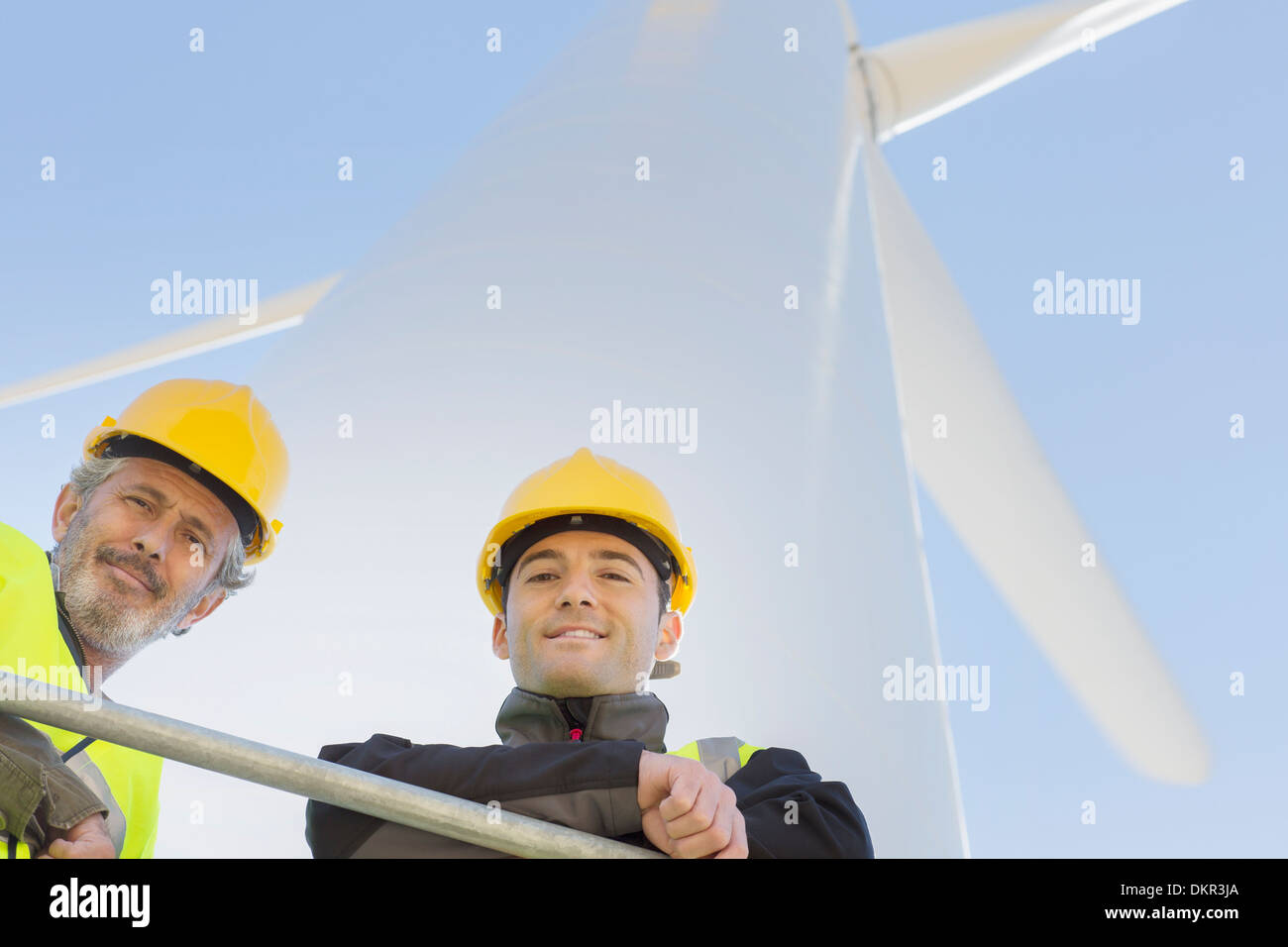 Lavoratori permanente sulla turbina eolica nel paesaggio rurale Foto Stock