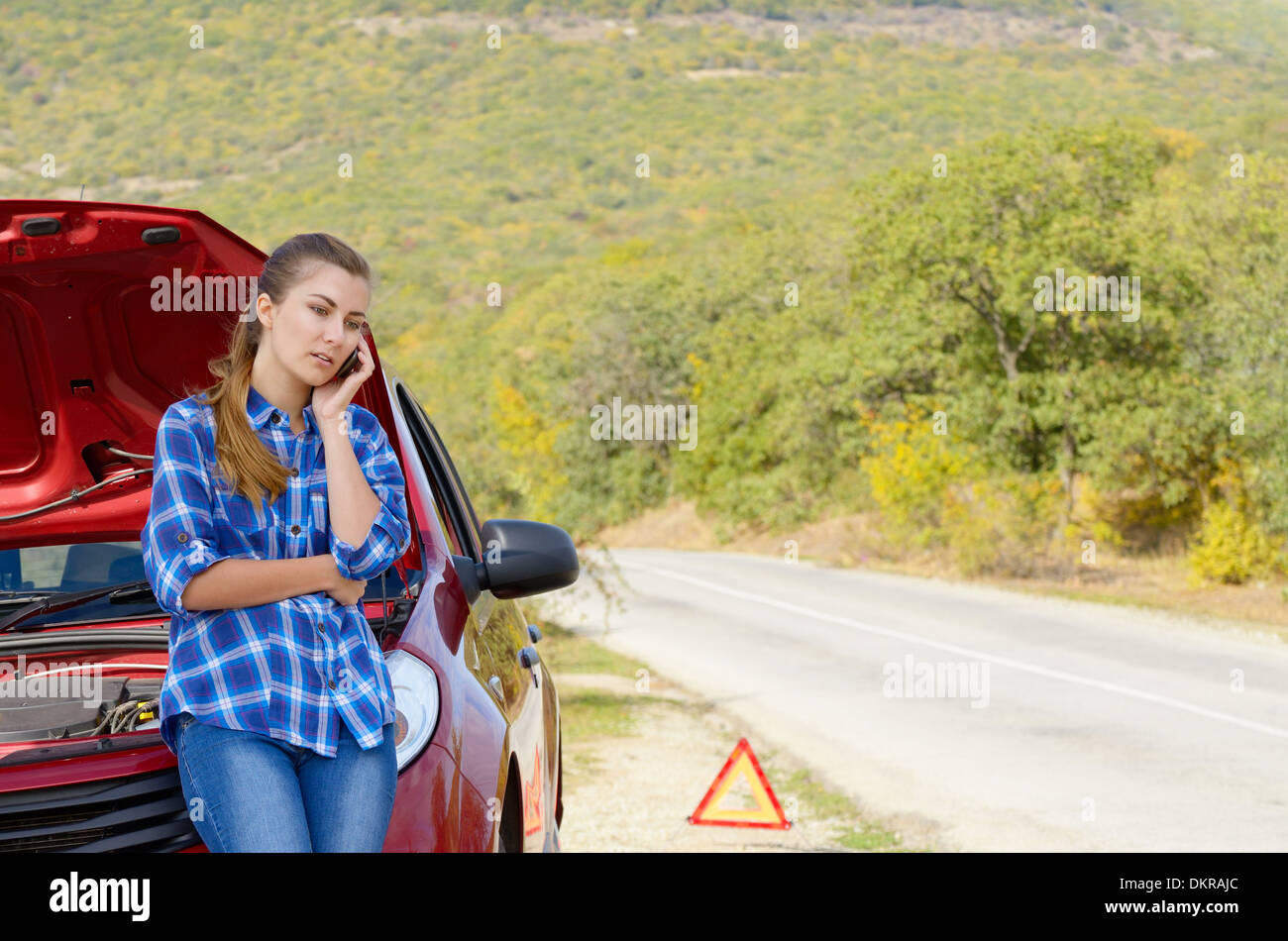 Giovane donna vicino a Broken auto parlando al telefono ha bisogno di assistenza Foto Stock