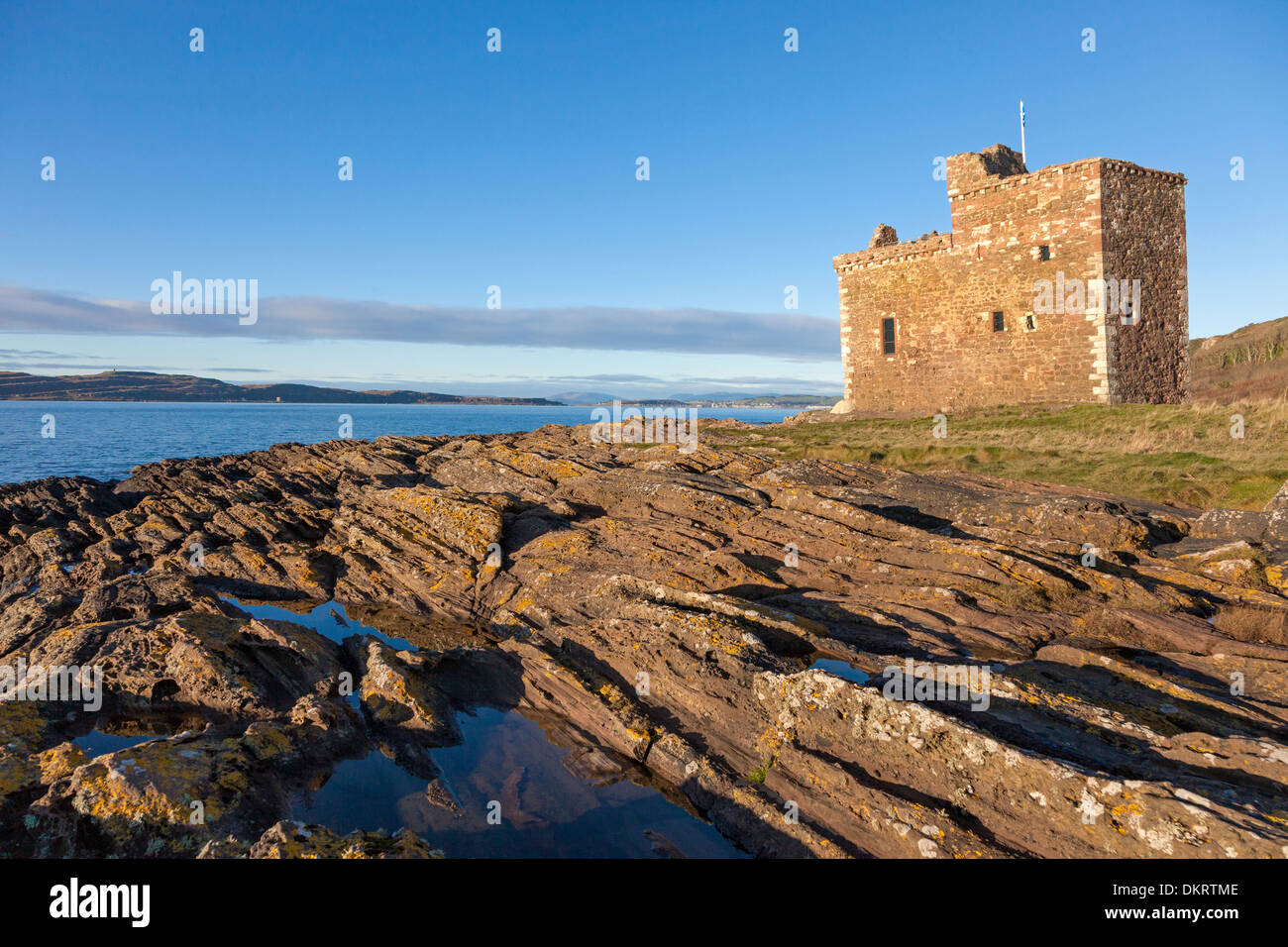 Il castello di Portencross, Ayrshire in Scozia, Regno Unito al tramonto con una vista verso nord lungo il Firth of Clyde all isola di Millport Foto Stock