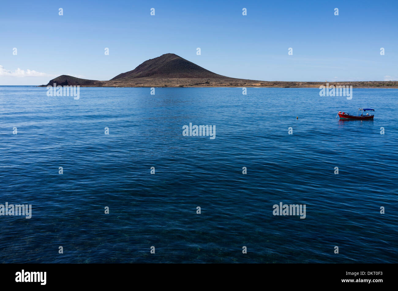 Lone rosso barca ormeggiata sul profondo blu del mare su una tranquilla giornata a El Medano, Tenerife, Isole Canarie, Spagna Foto Stock