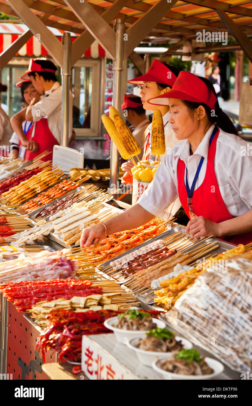 Le ragazze di vendita alimentari presso la famosa Wangfujing Street, il mercato notturno, Pechino, Repubblica Popolare Cinese, in Asia Foto Stock