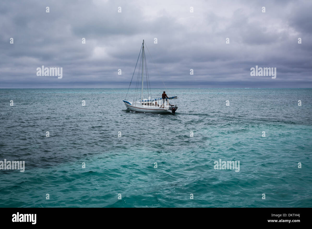Barca a vela Motori lontano dal Belize dock sulle acque turchesi del Mar dei Caraibi Foto Stock