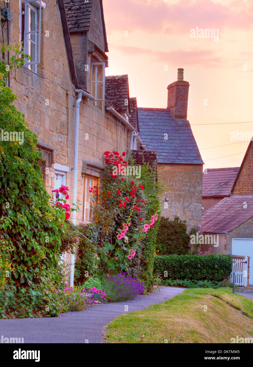 Cotswold cottage con hollyhocks e le rose al tramonto, Mickleton vicino a Chipping Campden, Gloucestershire, Inghilterra. Foto Stock