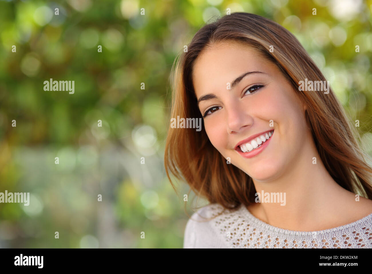 Bella donna trattamento viso con un perfetto sorriso bianco all'aperto con uno sfondo verde Foto Stock