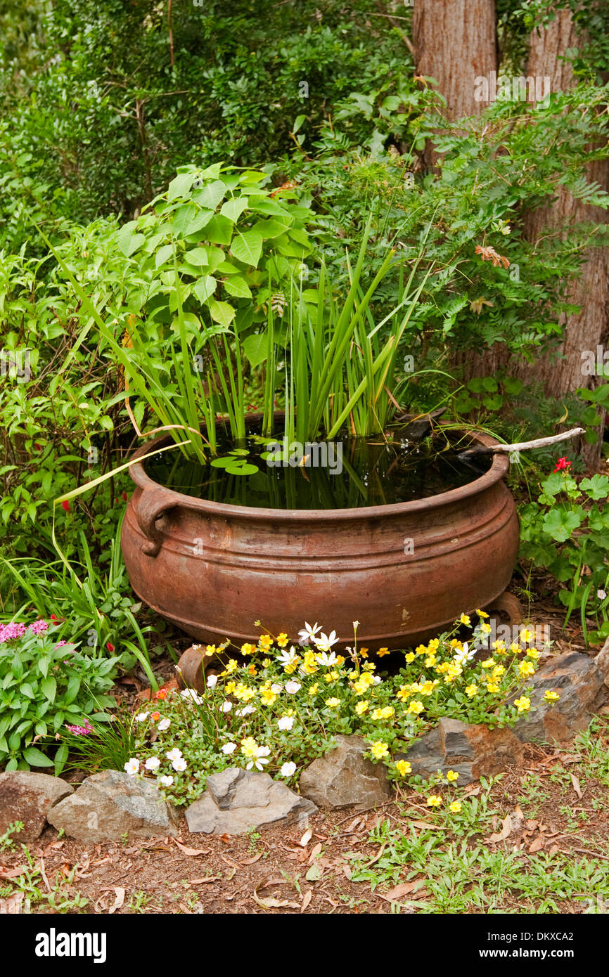 Grande calderone di metallo / vasca - spettacolare e unica funzione di acqua con piante acquatiche in letto giardino con fiori colorati Foto Stock