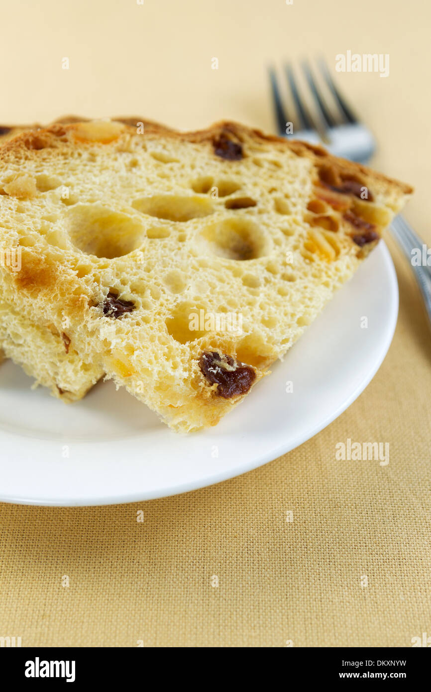 Closeup foto verticale di italiani freschi fette di torta su una piastra bianca lungo con forcella sul lato e testurizzato tabella panno sotto Foto Stock