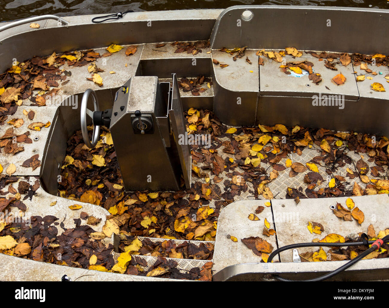 AMSTERDAM Olanda una barca in argento su uno dei canali coperti con foglie di autunno Foto Stock