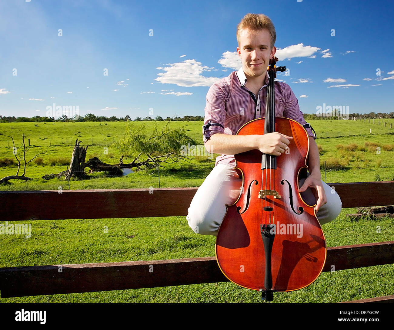 Un violoncello giocatore seduto su un recinto esterno con il suo celle Foto Stock