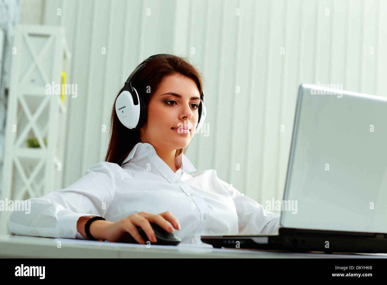 Giovane imprenditrice nelle cuffie al lavoro su un notebook in ufficio Foto Stock