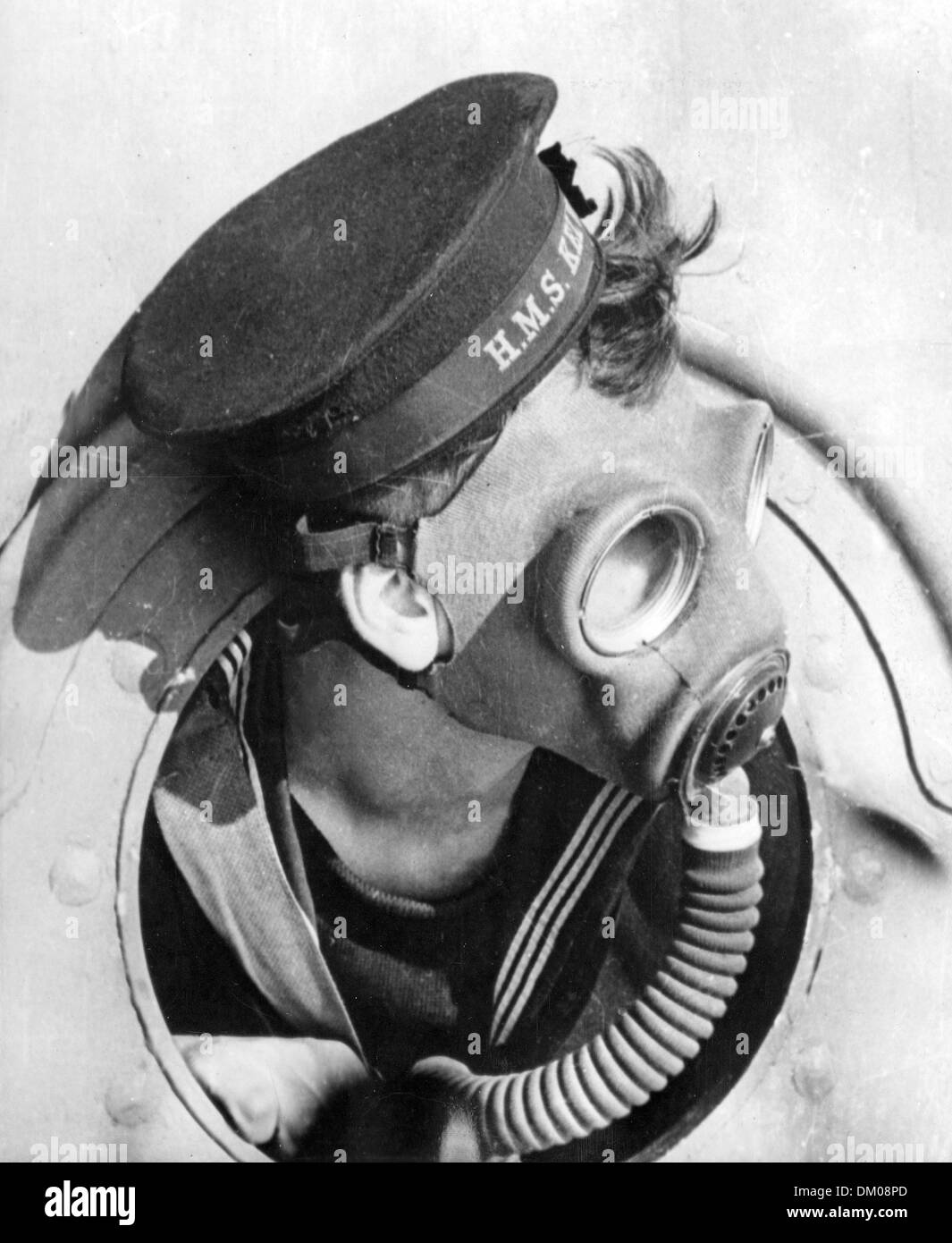 Un marinaio britannico coetanei attraverso un oblò di una nave da guerra durante il WW11. Indossa il problema standard smask ga. Foto Stock