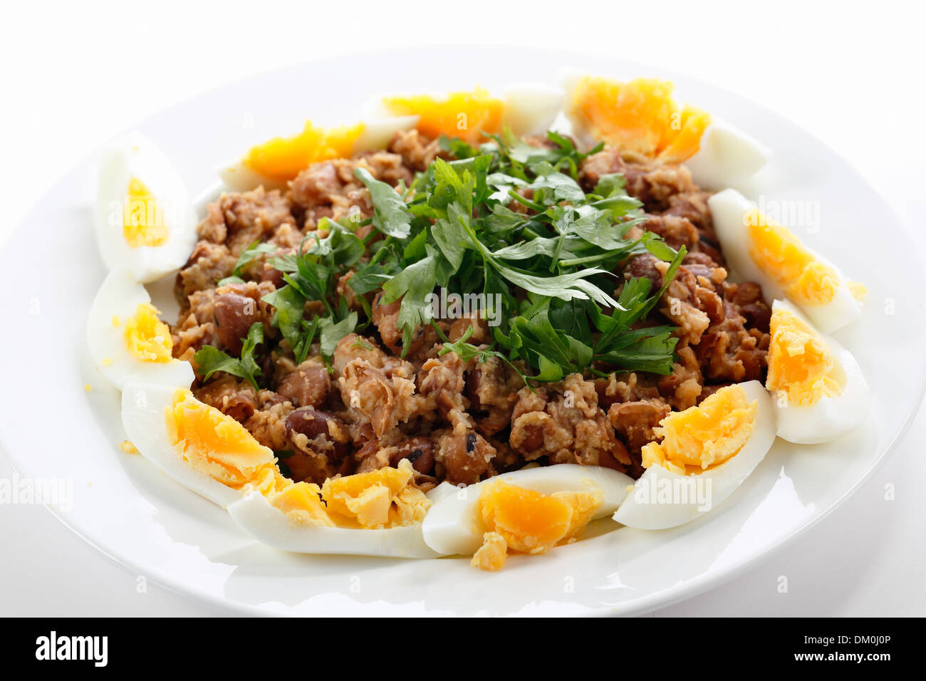 Fallo egiziano - o ful medames - su una piastra garneshed con fette di uova sode e il prezzemolo. Foto Stock