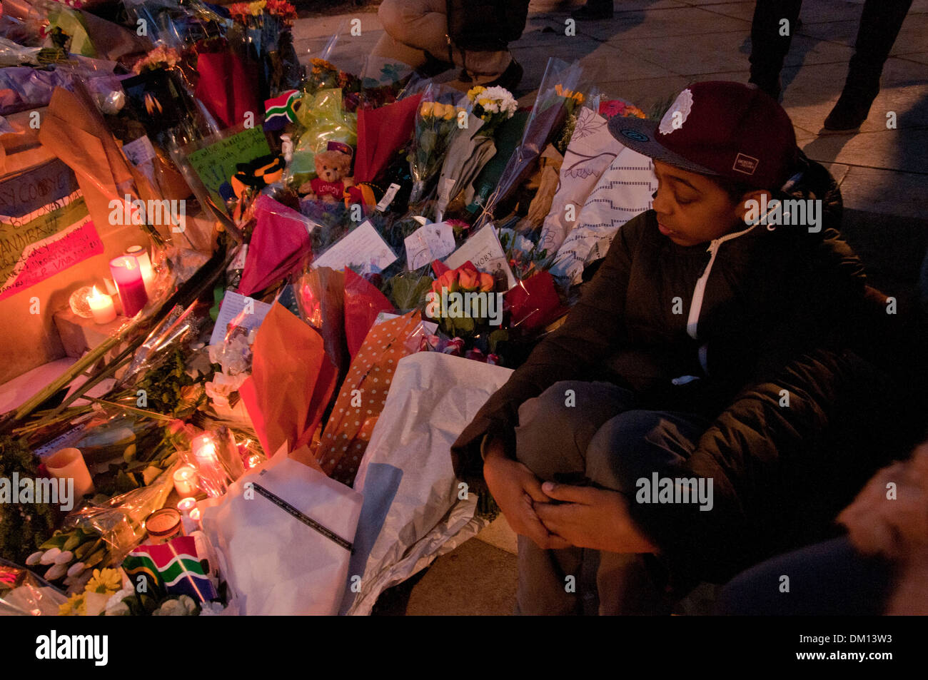 Come un omaggio a Nelson Mandela a bambini e adulti in lutto per la sua morte e portato fiori & messaggi e candele accese sotto il suo Foto Stock