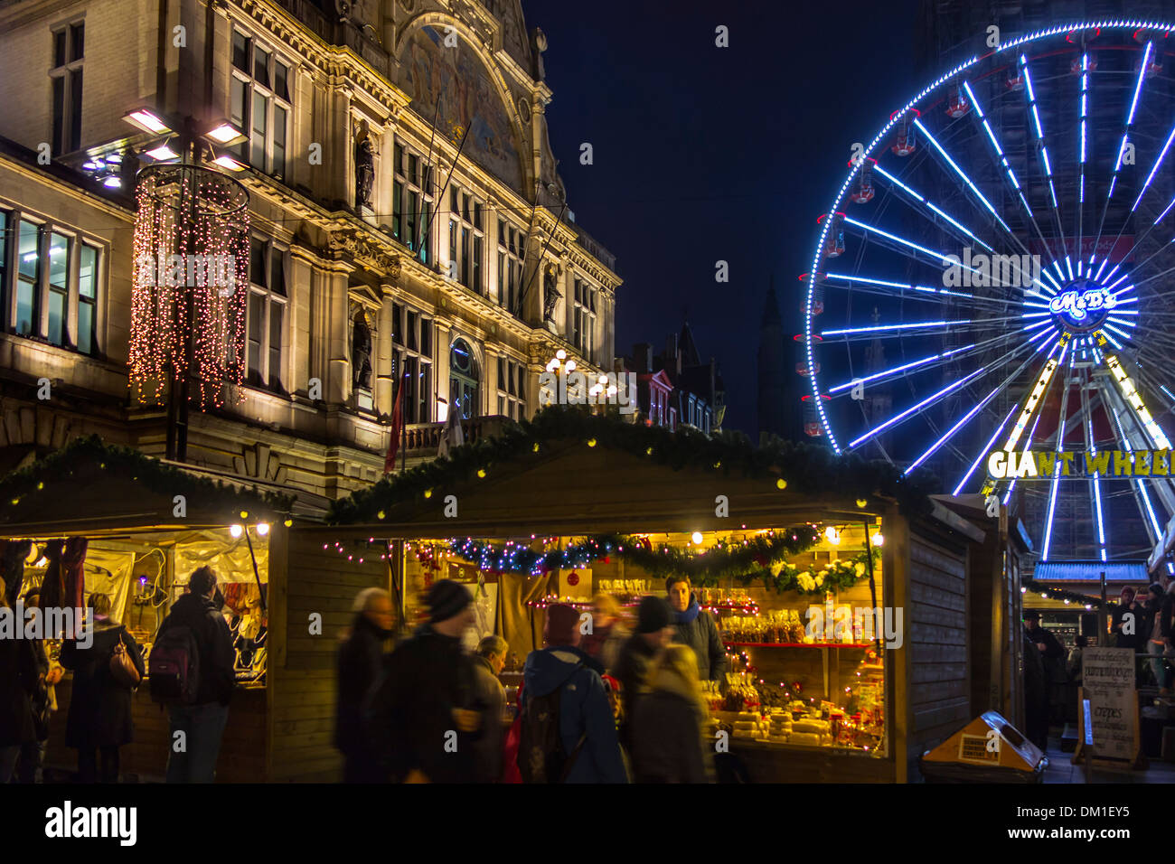 Illuminata ruota panoramica Ferris e people shopping a sera mercatino di Natale in inverno, Gand, Belgio Foto Stock