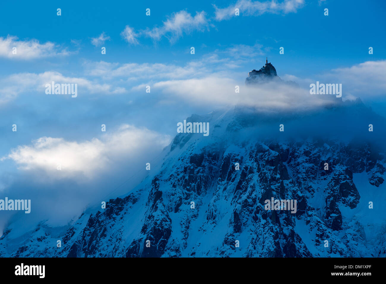 L'Aiguille du Midi che appare attraverso le nuvole, Mont Blanc, les Alpi, Alta Savoia, Francia Foto Stock