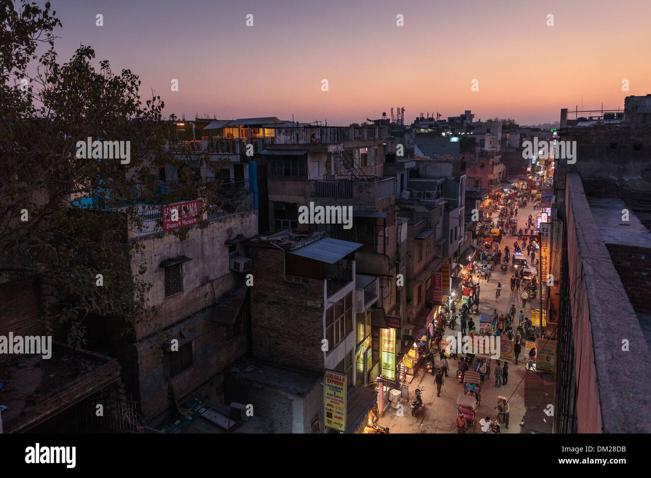 Pedoni e risciò affollano Pahar Ganj Street a nuova Delhi, in India, come si vede da un ristorante sul tetto dopo il tramonto. Foto Stock