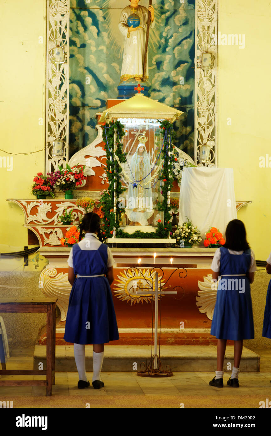Ragazze indiano pregando davanti di un cattolico la statua di Maria Foto Stock