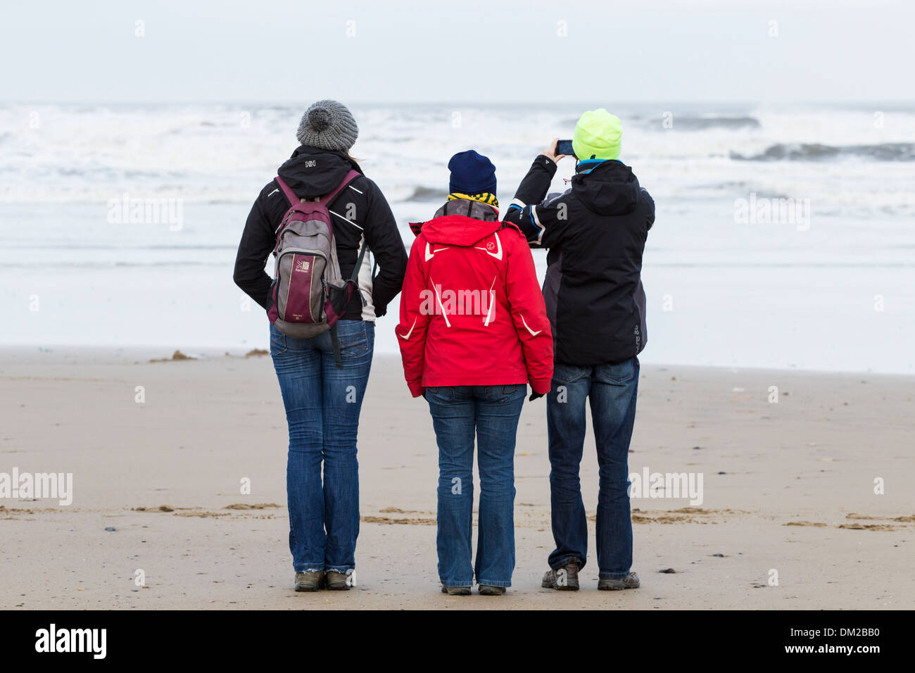 La gente camminare sulla spiaggia e scattare fotografie seguenti Dicembre 2013 picchi di marea tempeste nel Regno Unito. Foto Stock
