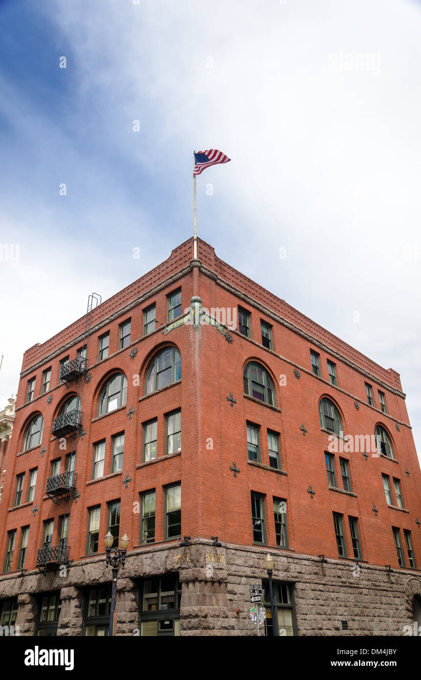 Storico edificio di mattoni rossi nel centro di Portland, Oregon con la bandiera americana sventola alto sopra di esso Foto Stock