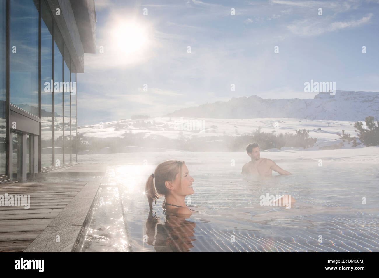 Donna e uomo seduto in una piscina riscaldata in inverno con acqua di cottura a vapore, Alto Adige, Trentino Alto Adige, Italia Foto Stock