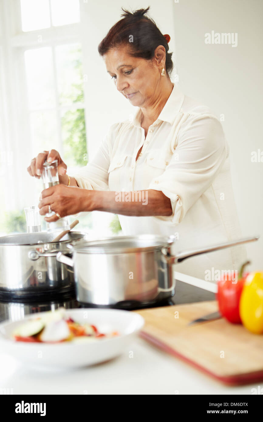 Senior donna indiana la cottura di pasto a casa Foto Stock