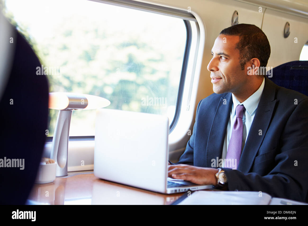 Imprenditore il pendolarismo per lavorare sul treno e utilizzando computer portatile Foto Stock