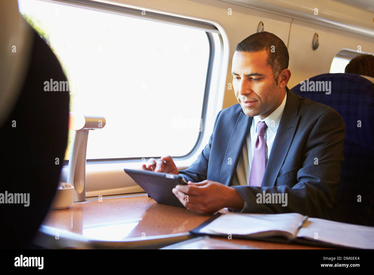 Imprenditore il pendolarismo sul treno usando tavoletta digitale Foto Stock
