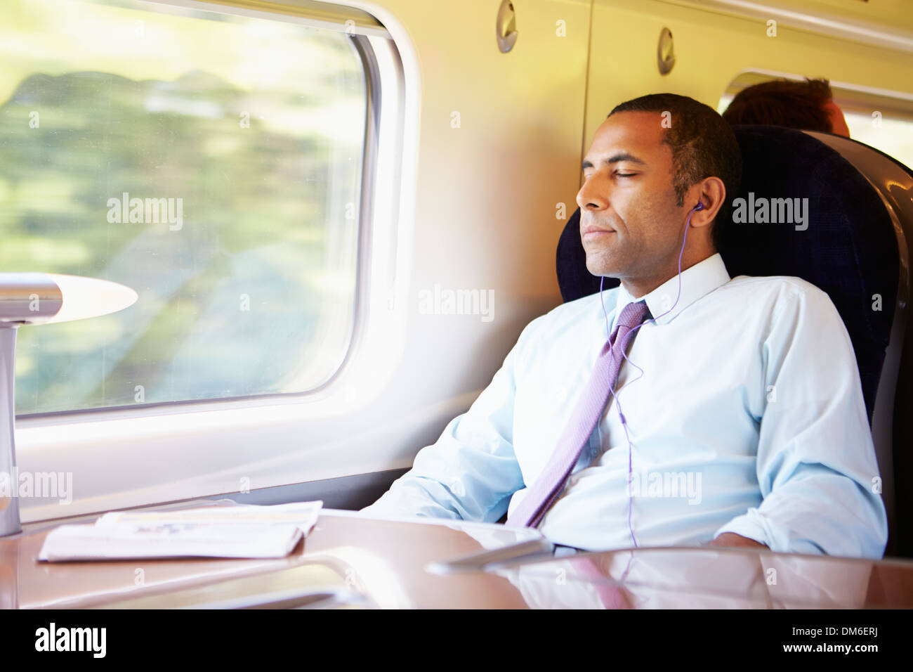 Imprenditore rilassante sul treno ascoltando musica Foto Stock