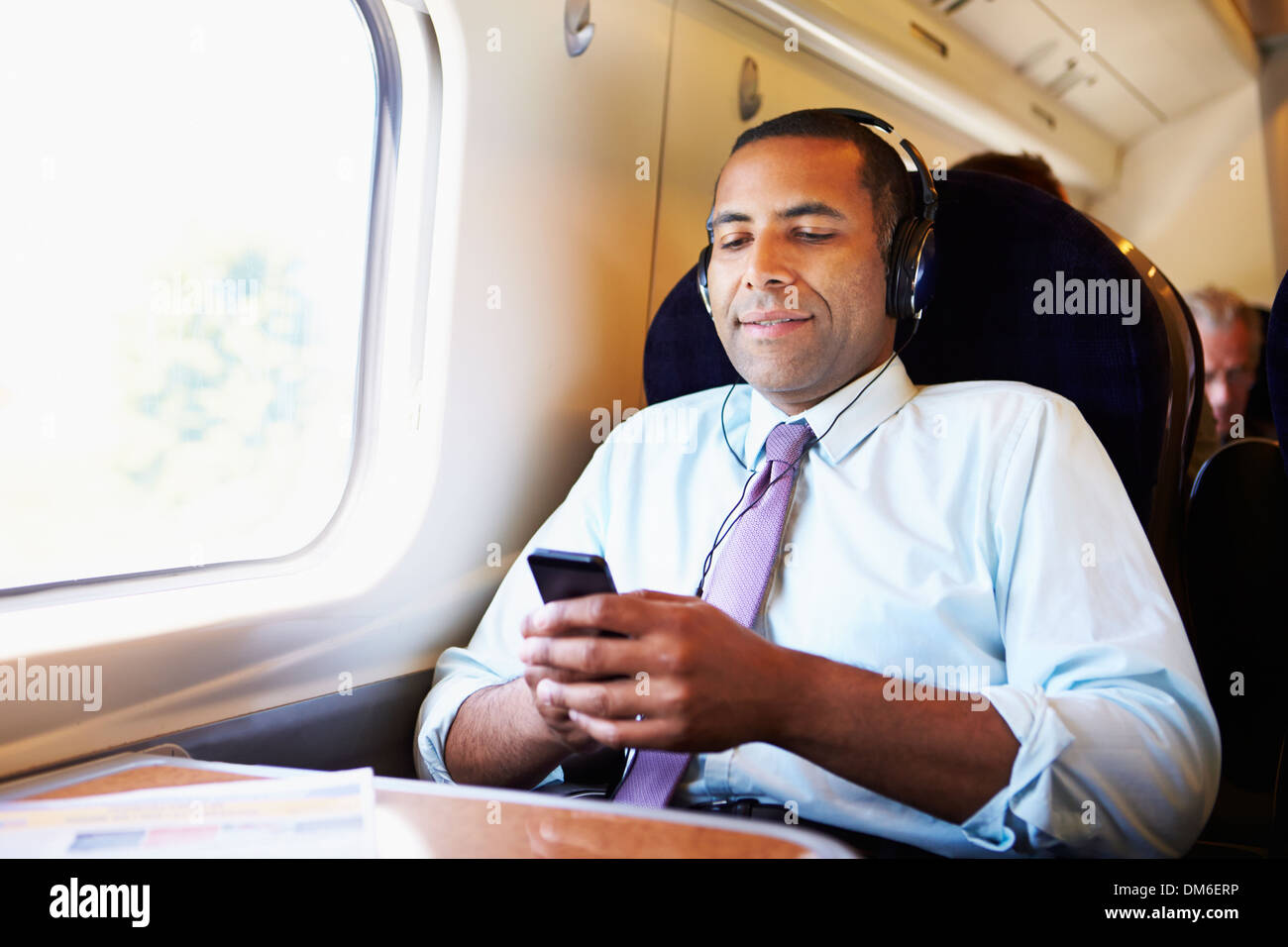 Imprenditore rilassante sul treno ascoltando musica Foto Stock