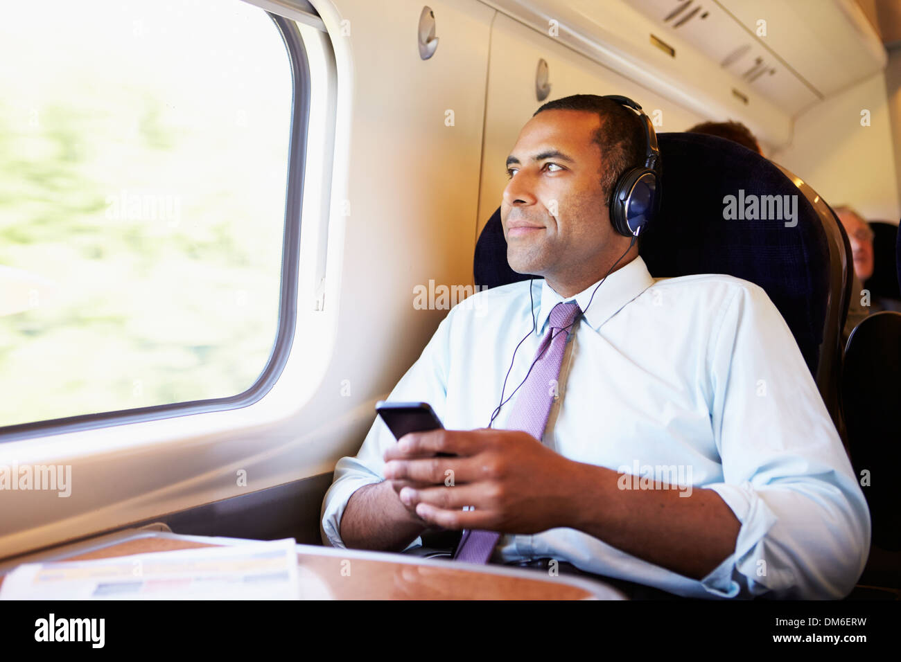 Imprenditore rilassante sul treno ascoltando musica Foto Stock