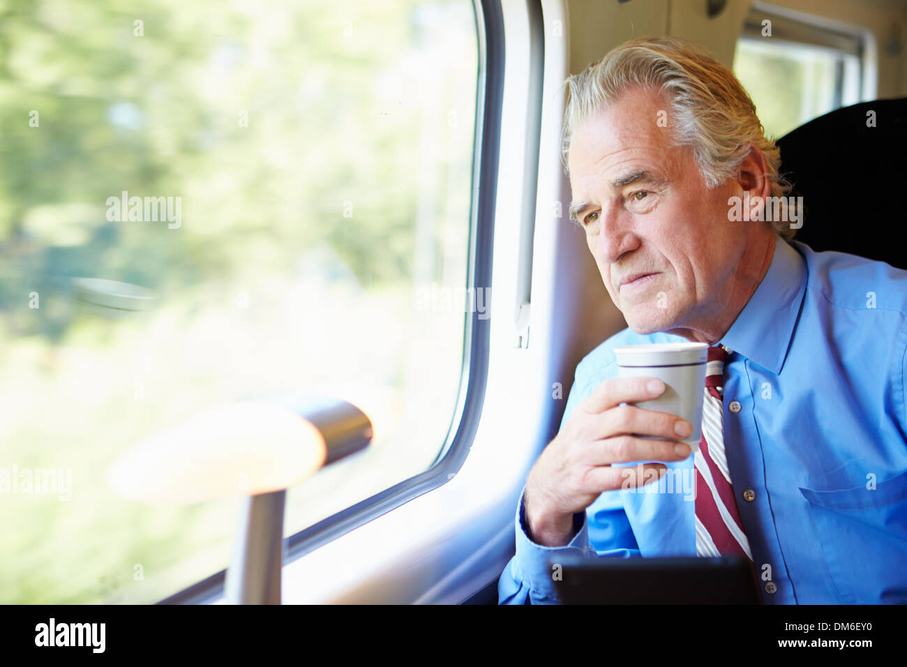 Imprenditore rilassante sul treno con la tazza di caffè Foto Stock